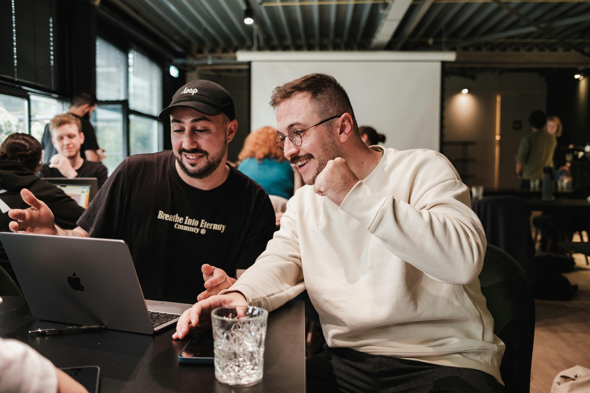 2 junge Männer unterhalten sich gut gelaunt, während sie auf einen Laptop schauen.